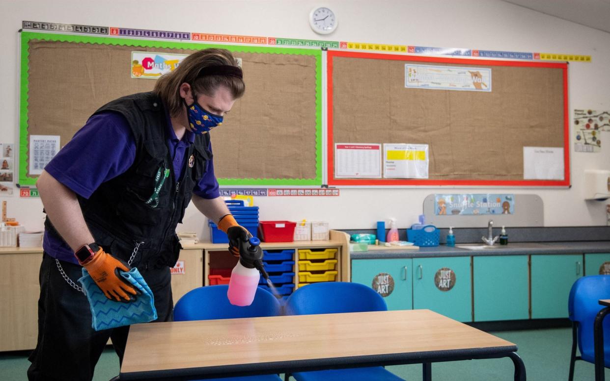 Joshua Lee disinfects tables at Queen's Hill Primary School in Costessey near Norwich, -  Joe Giddens / PA