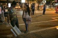 Left-wing protesters, one holding a placard bearing the logo of Peace Now, an Israeli NGO that tracks and opposes Jewish settlement in the occupied West Bank and East Jerusalem, talk during a rally in Tel Aviv, in this October 24, 2015 file picture. REUTERS/Baz Ratner/Files