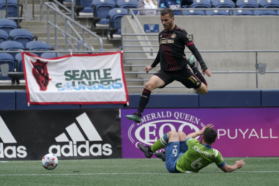 Atlanta United midfielder Brooks Lennon (11) jumps over Seattle Sounders midfielder Joao Paulo during the first half of an MLS soccer match, Sunday, May 23, 2021, in Seattle. (AP Photo/Ted S. Warren)