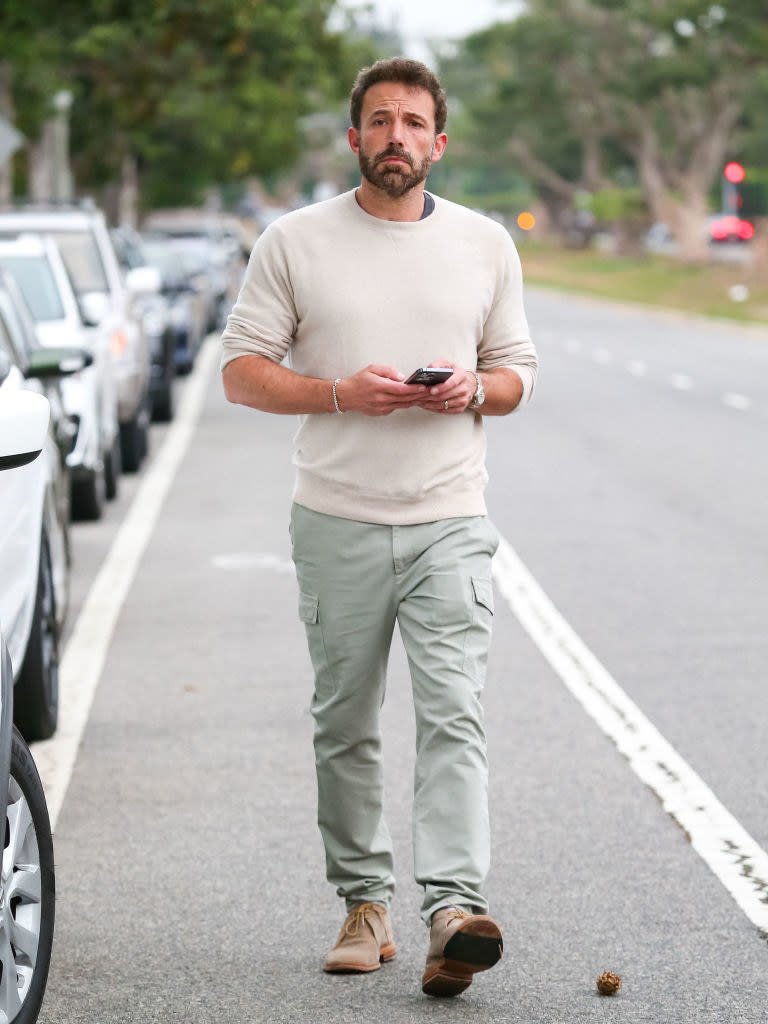 Ben walking on the street and holding a cellphone