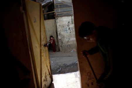 A Palestinian girl looks on as a man cleans his house at Shati refugee camp in Gaza City March 14, 2018. REUTERS/Mohammed Salem