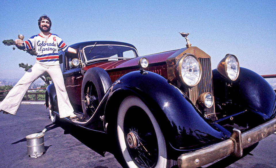 Keith Moon, The Who's Celebrated Drummer Standing On The Running Board Of His Classic Rolls-Royce Car On Mulholland Drive In The Hollywood Hills In Los Angeles, California, June 1976.