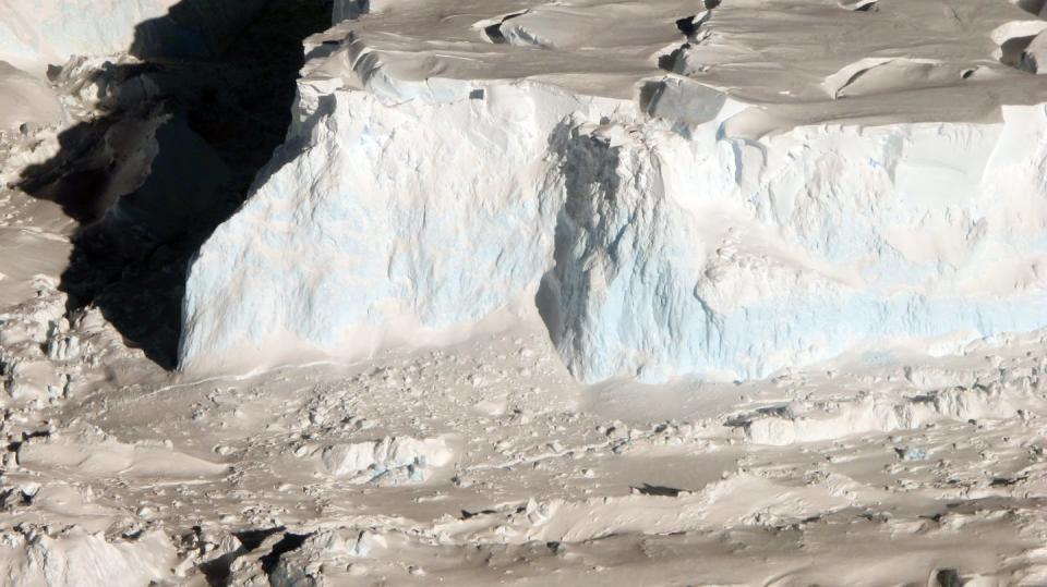 An aerial view of the high front of the Thwaites Ice Shelf, where icebergs calve and enter the ocean.