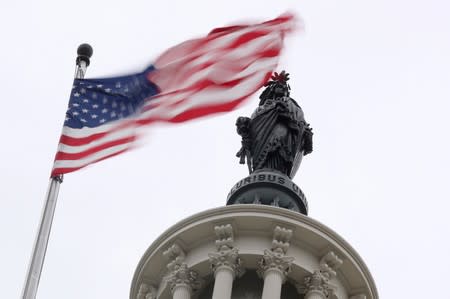 The U.S. flag flies near the Statue of Freedom atop the U.S. Capitol in Washington