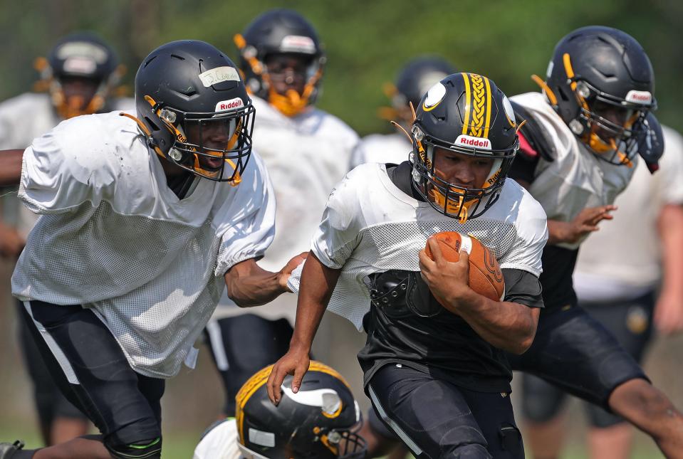 North running back Elijah Gervins rushes for yards as Jalen Coppinger, left, attempts to bring him down during practice Aug. 3 at North High School.