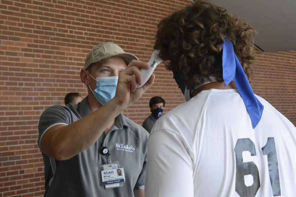 Michael Toth, athletic trainer, left, takes Gavin Guers' temperature before football practice at Blue Mountain High School in Orwigsburg, Pa., on Monday, Aug. 24, 2020. (Lindsey Shuey/The Republican-Herald via AP)