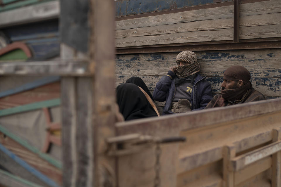 Men and women sit in the back of a truck as they wait to be screened by U.S.-backed Syrian Democratic Forces (SDF) after being evacuated out of the last territory held by Islamic State militants, in the desert outside Baghouz, Syria, Wednesday, Feb. 27, 2019. (AP Photo/Felipe Dana)