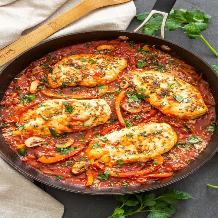 A skillet of chicken in a thick tomato sauce