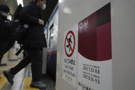People wearing protective masks to help curb the spread of the coronavirus get on a subway with a banner of Tokyo 2020 Olympic and Paralympic games in Tokyo Thursday, Jan. 14, 2021. The Japanese capital confirmed more than 1500 new coronavirus cases on Thursday. (AP Photo/Eugene Hoshiko)