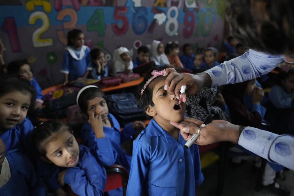 A health worker administers a polio vaccine to a child at a school, in Lahore, Pakistan, Monday, Oct. 24, 2022. (AP Photo/K.M. Chaudary)
