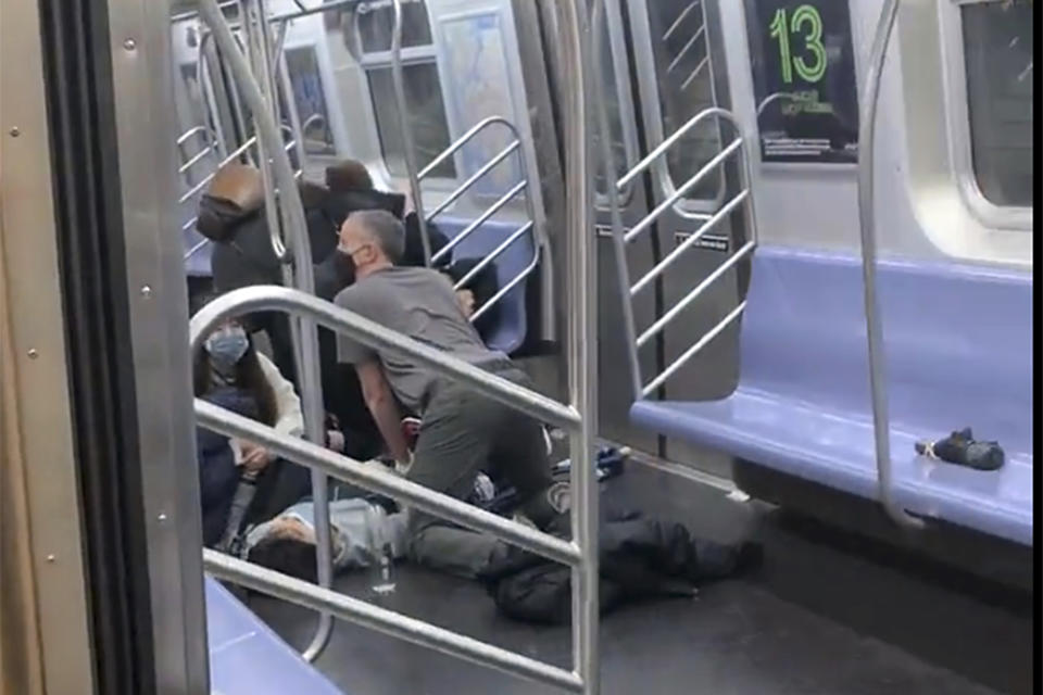 This photo provided by Will B Wylde, a person is aided in a subway car in the Brooklyn borough of New York, Tuesday, April 12, 2022. A gunman filled a rush-hour subway train with smoke and shot multiple people Tuesday, leaving wounded commuters bleeding on a Brooklyn platform as others ran screaming, authorities said. Police were still searching for the suspect. (Will B Wylde via AP)