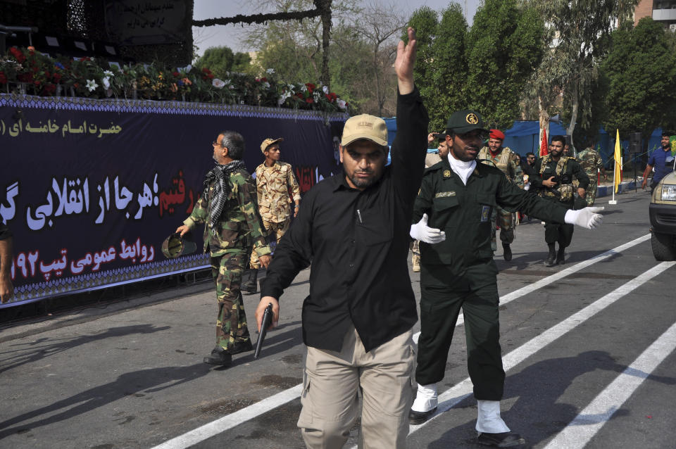 In this photo provided by the Iranian Students' News Agency, ISNA, security forces try to control the scene after a shooting during a military parade marking the 38th anniversary of Iraq's 1980 invasion of Iran, in the southwestern city of Ahvaz, Iran, Saturday, Sept. 22, 2018. Gunmen attacked the military parade, killing at least eight members of the elite Revolutionary Guard and wounding 20 others, state media said. (AP Photo/ISNA, Behrad Ghasemi)