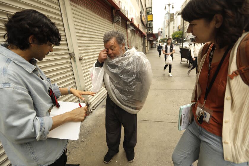 LOS ANGELES, CA - JUNE 7, 2022 - - Dr. Shayan Rab, left, a street psychiatrist with the Los Angeles County Dept. of Mental Health, who leads the Homeless Outreach & Mobile Engagement (HOME) team and Karla Bennett, Mental Health Clinical Supervisor with HOME, check in with client Juan Luna who suffers from mental illness and lives homeless in downtown Los Angeles on June 7, 2022. Dr. Rab and Bennett hope to eventually get Luna into housing where they can continue treating his mental illness. Dr. Rab tells Luna that he can get him a proper coat but Luna said the plastic keeps his warm.(Genaro Molina / Los Angeles Times)