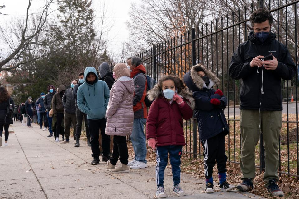 Children wait with their father as they wait in a line spanning several blocks in order to be tested for COVID-19, Tuesday, Dec. 21, 2021, at a Curative testing kiosk outside an elementary school in northwest Washington.