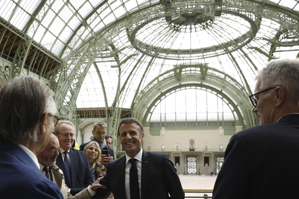 French President Emmanuel Macron smiles as he visits the Grand Palais ahead of the Paris 2024 Olympic Games in Paris, Monday, April15, 2024. The Grand Palais will host the Fencing and Taekwondo competitions during the Paris 2024 Olympic Games. (Yoan Valat, Pool via AP)