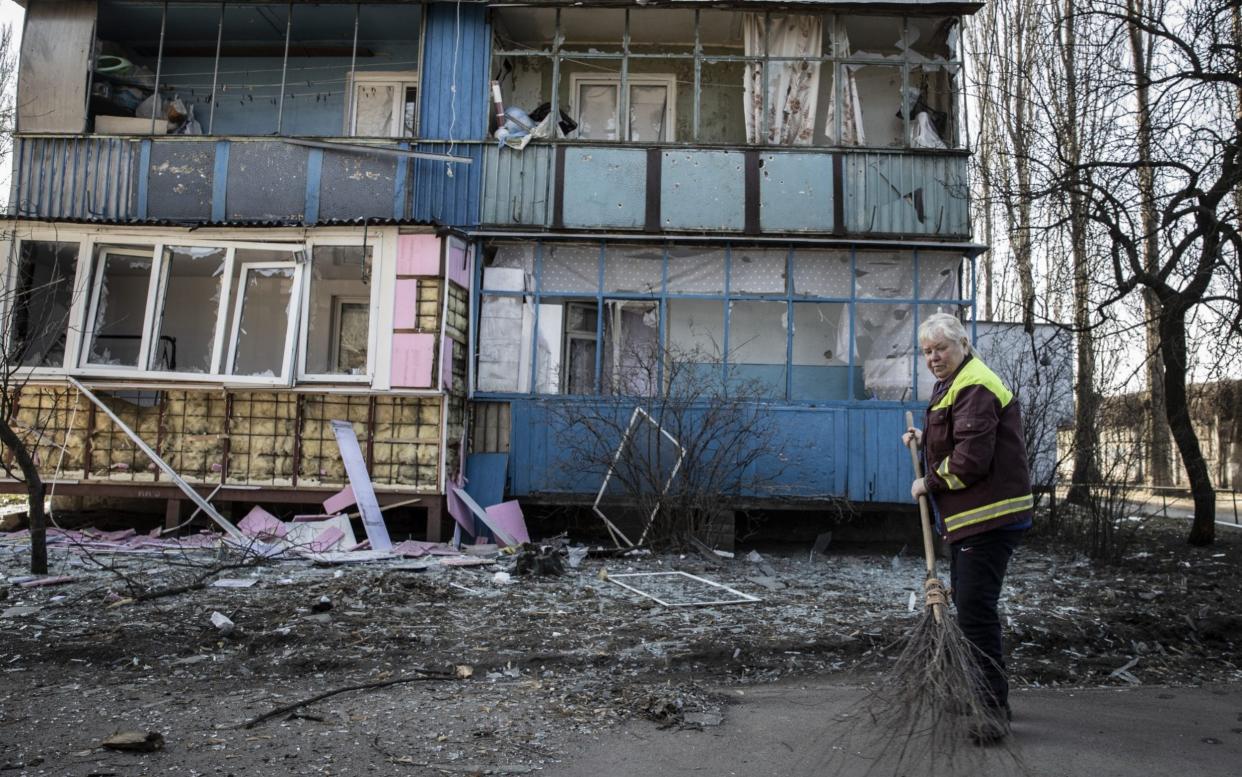 A Ukrainian woman cleans a site damaged by Russian attacks in Kyiv, Ukraine on March 23, 2022.  - Emin Sansar/Anadolu Agency