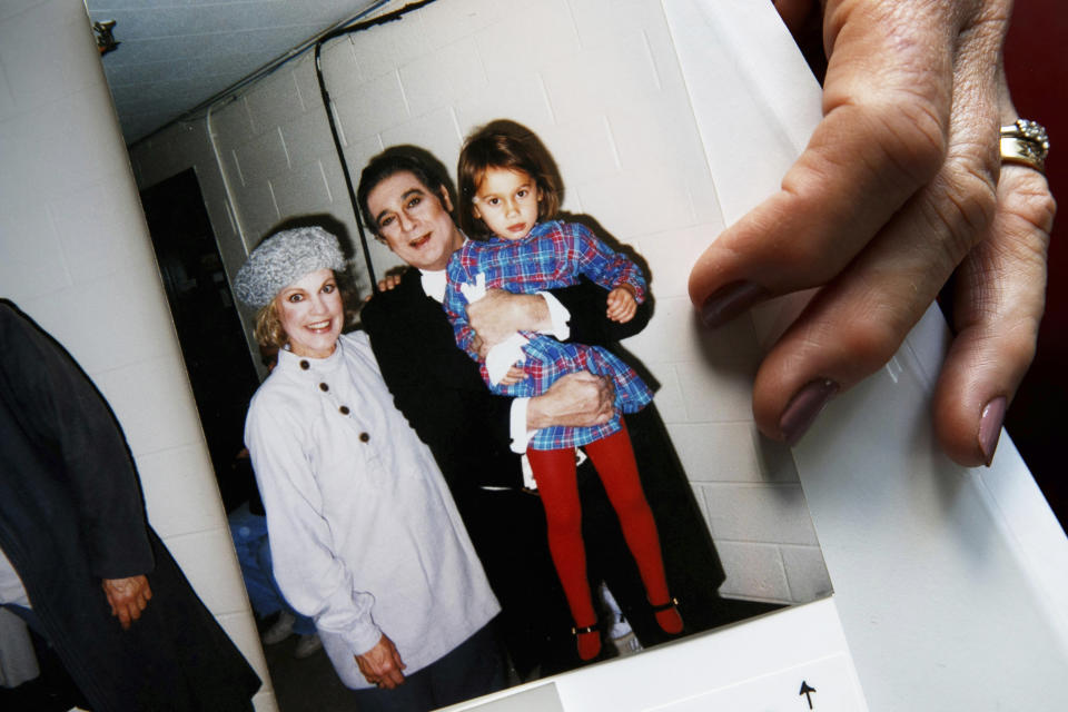 Opera singer Patricia Wulf holds a 1998 photo of herself, left, with opera star Placido Domingo holding her 4-year old daughter after a performance of "Fedora" at the Washington Opera, at her home in rural northern Virginia, on Friday, July 12, 2019. In interviews, Wulf said Domingo repeatedly propositioned her as she walked off stage, often knocked on her dressing room door asking to come in and she tried to dodge his advances by hiding from him. She said she repeatedly told the opera superstar who was also artistic director at Washington Opera that she wasn't interested and each time would wonder, "Did I just ruin my career?" (AP Photo/Jacquelyn Martin)