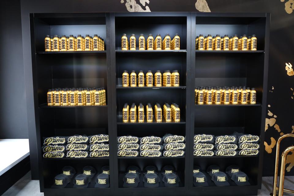 Black shelves with gold Prime bottles and branded Prime t-shirts and caps.
