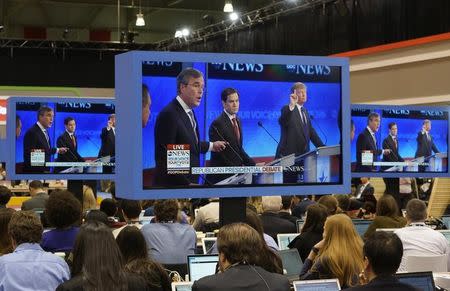 Republican U.S. presidential candidate businessman Donald Trump (R) and former Governor Jeb Bush (L) debate each other as U.S. Senator Marco Rubio (C) stands between the two men as journalists watch the debate on monitors in the media filing center during the Republican U.S. presidential candidates debate sponsored by ABC News at Saint Anselm College in Manchester, New Hampshire February 6, 2016. REUTERS/Rick Wilking