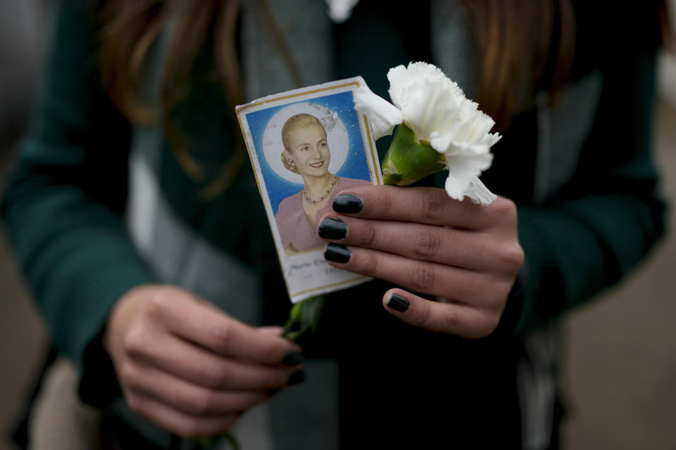 A woman holds a photo of Argentina's late first lady Maria Eva Duarte de Peron, better known as Evita, as she waits her turn to visit Evita's tomb in Buenos Aires, Argentina, Tuesday, July 26, 2022. Argentines commemorate the 70th anniversary of the death of their most famous first lady, who died of cancer on July 26, 1952 at the age of 33. (AP Photo/Natacha Pisarenko)