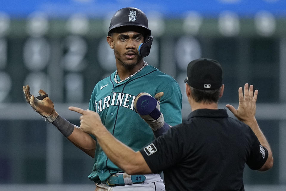 Seattle Mariners' Julio Rodriguez, left, is told he has to return to first base by umpire Mark Wegner after stealing second base because Mariners' Ty France had been called out on batter interference during the eighth inning of a baseball game against the Houston Astros, Saturday, Aug. 19, 2023, in Houston. (AP Photo/Kevin M. Cox)