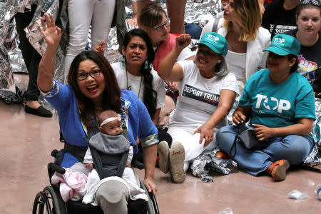 FILE PHOTO: U.S. Senator Tammy Duckworth (D-IL), with her daughter Maile Pearl Bowlsbey, cheers on demonstrators calling for "an end to family detention" and in opposition to the immigration policies of the Trump administration, as they are arrested by U.S. Capitol Police at the Hart Senate Office Building on Capitol Hill in Washington, U.S. June 28, 2018. REUTERS/Jonathan Ernst/File Photo