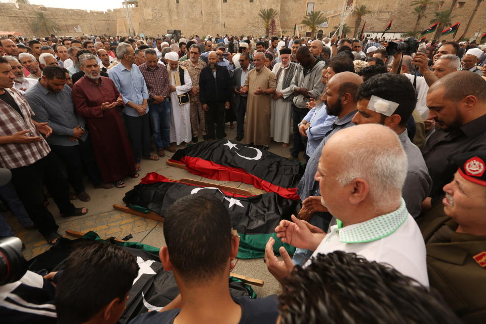 FILE - In this April 24, 2019 file photo, mourners pray for fighters killed in airstrikes by warplanes of Field Marshal Khalifa Hifter's forces, in Tripoli, Libya. After years of assassinations, bombings and militia firefights, Libya’s eastern city of Benghazi finally feels safe again, but the city center lies in ruins, thousands remain displaced, and forces loyal to Hifter, who now controls eastern Libya, have cracked down on dissent. Benghazi offers a glimpse of what may befall the capital, Tripoli, where Hifter’s forces launched an offensive in April against rival militias loosely allied with a weak, U.N.-recognized government. (AP Photo/Hazem Ahmed, File)