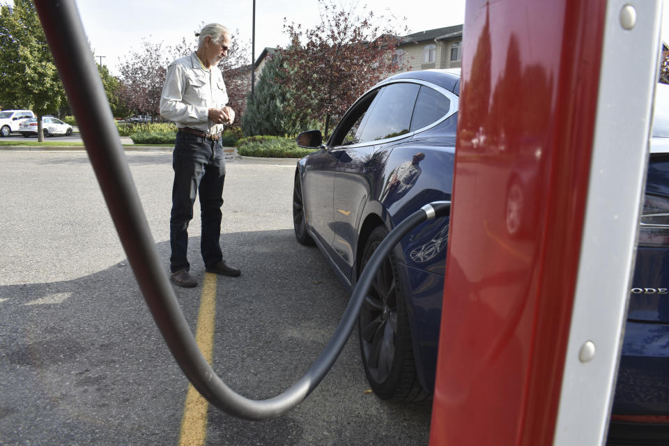 Bob Palrud of Spokane, Wash. speaks with a fellow electric vehicle owner who is charging up at a station along Interstate 90, on Wednesday Sept. 14, 2022, in Billings, Mont. Palrud says distances between EV charging stations are always on his mind during lengthy journeys across the U.S. West where such infrastructure remains sparse. (AP Photo/Matthew Brown)