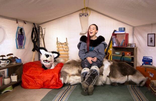 Singer Rita Claire and husky Qimmiq are shown in a scene from the television show Anaana's Tent, filmed in Nunavut. A new Inuit-language television channel called Uvagut TV launches Monday. The name means 'Our TV' in English.  (Arvaaq Media Inc./The Canadian Press  - image credit)
