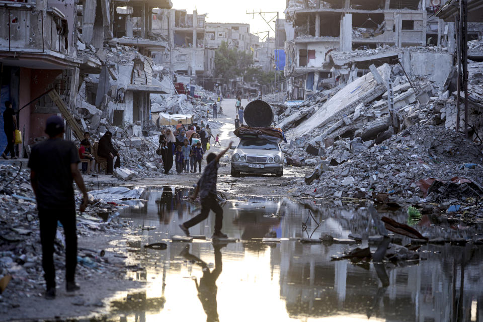 Palestinians displaced by the Israeli air and ground offensive on the Gaza Strip, walk past sewage flowing into the streets of the southern town of Khan Younis, Gaza Strip, Thursday, July 4, 2024. (AP Photo/Jehad Alshrafi)