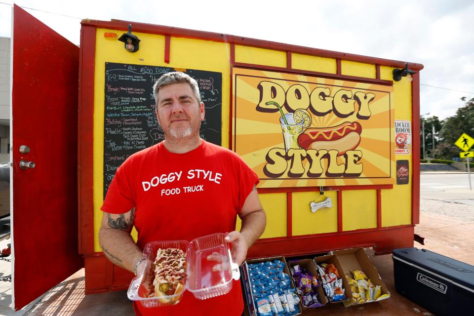 Jeremy Mathis holds a K-9, a hot dog with bacon, jalapeños, cream cheese and pepper jack cheese on it, at his food truck "Doggy Style" that opened in April.