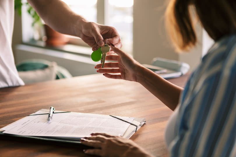 Cropped image of owner giving house keys to tenant after filling rental forms