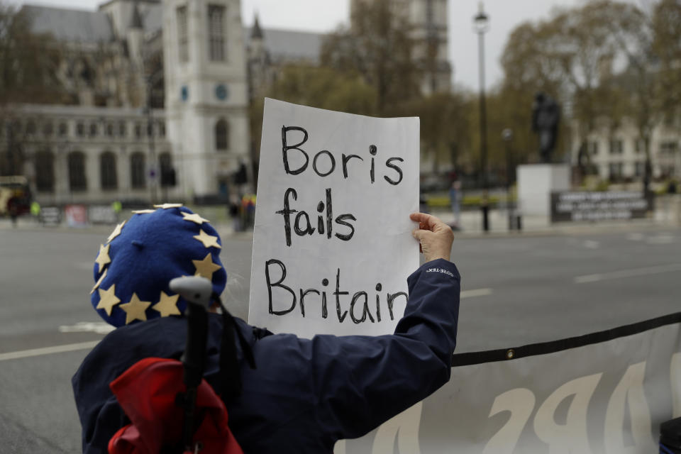 FILE - In this Wednesday, April 28, 2021 file photo, an anti-Brexit protester holds a placard at the Houses of Parliament, in London. It was late on Christmas Eve in 2020 when the European Union and Britain finally clinched a Brexit trade deal after years of wrangling, threats and missed deadlines to seal their divorce. Such was the bile and bad blood stirred up by the diplomatic brinkmanship and bitter divorce that, two months from another Christmas, insults of treachery and duplicitousness are flying again. (AP Photo/Matt Dunham, File)