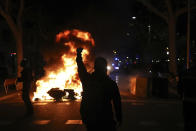 A protestors raises his fist at police across a burning barricade during clashes between protestors and police in Barcelona, Spain, Tuesday, Oct. 15, 2019. Thousands of Catalan separatists are protesting for a second straight day over the Spanish court ruling that imprisoned nine independence leaders and the conviction of three others. (AP Photo/Emilio Morenatti)