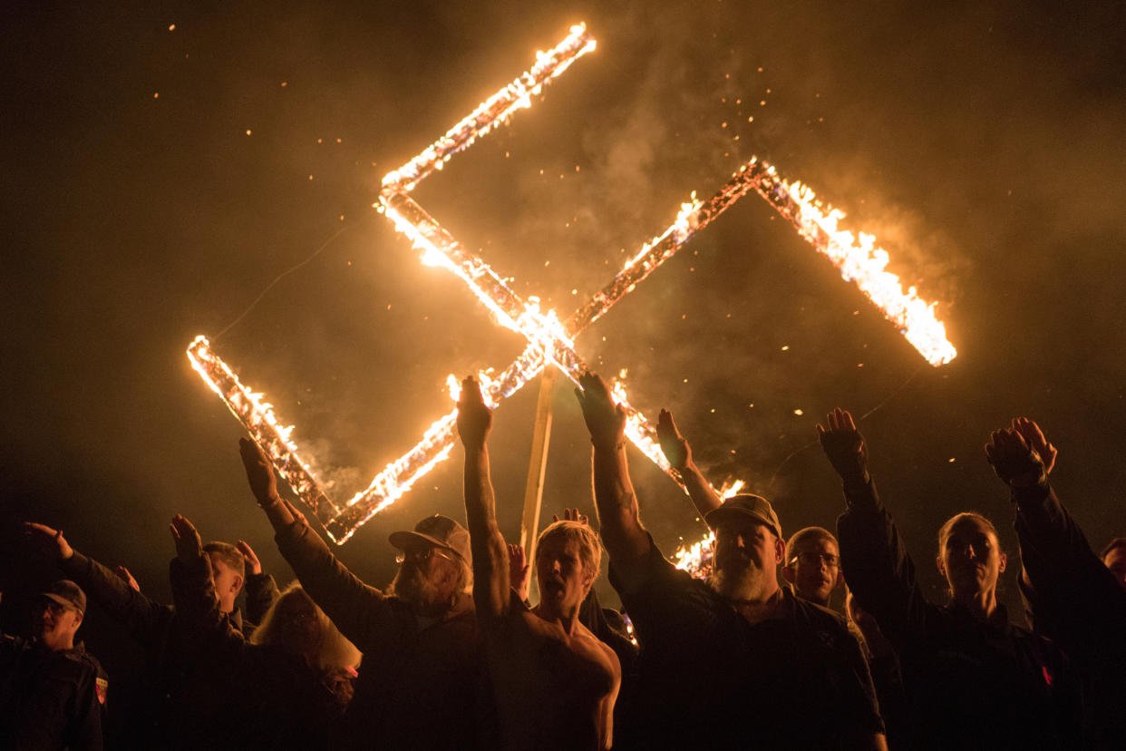 Supporters of the National Socialist Movement, a white nationalist political group, give Nazi salutes while taking part in a swastika burning at an undisclosed location in Georgia, U.S. on April 21, 2018. (Go Nakamura/Reuters)