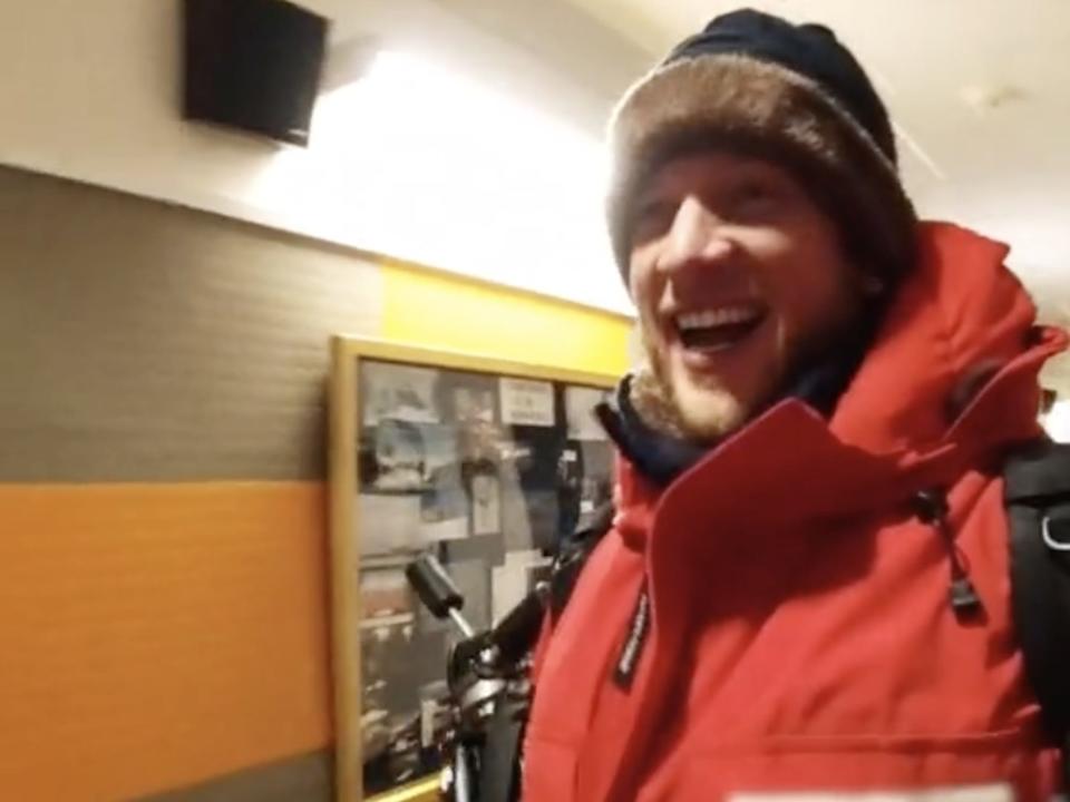 Josiah Horneman, a man, is wearing a heavy red coat whilst walking in a corridor at the Amundsen-Scott South Pole Station.