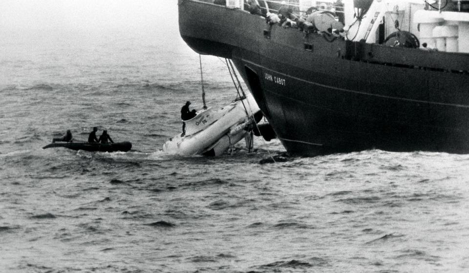 Divers begin to open the hatch of the minature submarine Pisces III as she breaks water under the John Cabot after being hauled from the Atlantic seabed off Cork (PA)