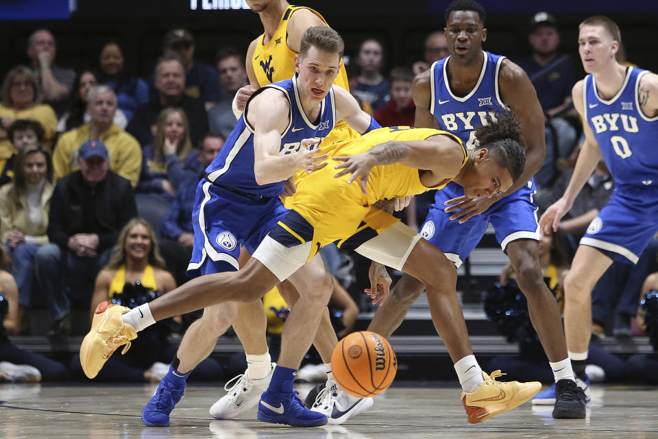 West Virginia guard RaeQuan Battle, front, is defended by BYU guard Spencer Johnson, left, during the first half of an NCAA college basketball game Saturday, Feb. 3, 2024, in Morgantown, W.Va. (AP Photo/Kathleen Batten)
