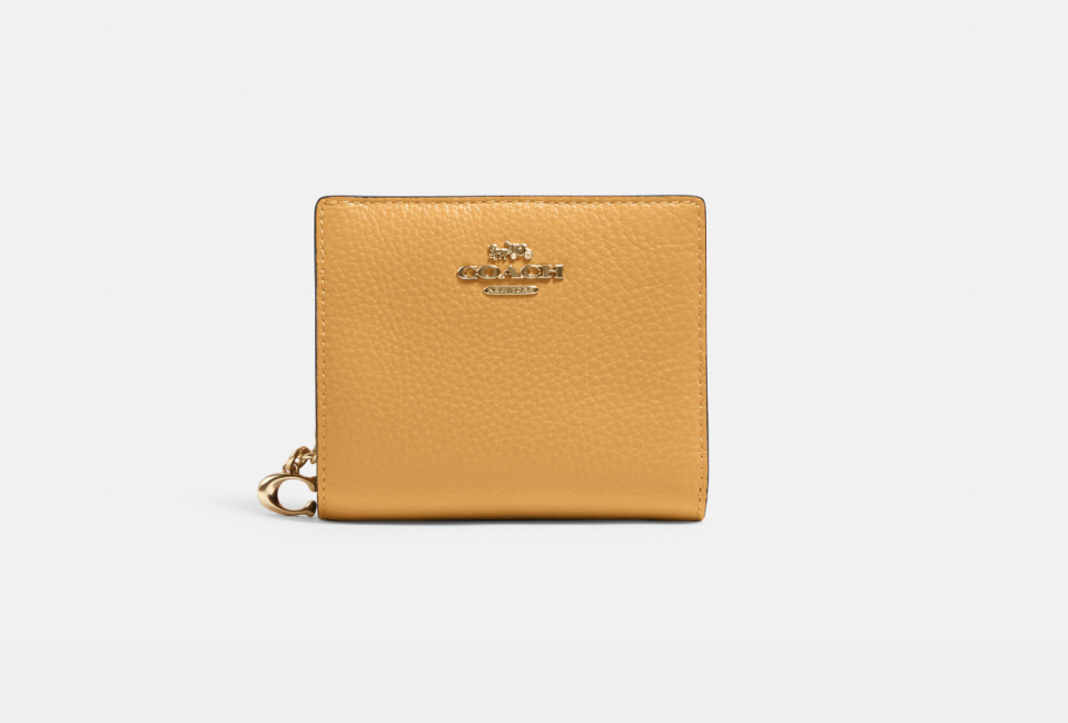 Cartera plegable de Coach Outlet en plateado/púrpura (Foto vía Coach Outlet)