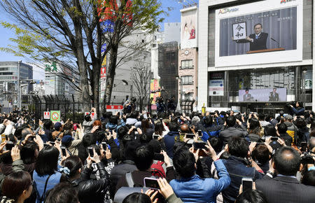 People gather to watch a huge screen broadcasting live reports on the unveiling of the new era name 'Reiwa' by Japan's Chief Cabinet Secretary Yoshihide Suga in Tokyo, Japan, April 1, 2019, in this photo taken by Kyodo. Mandatory credit Kyodo/via REUTERS ATTENTION EDITORS - THIS IMAGE WAS PROVIDED BY A THIRD PARTY. MANDATORY CREDIT. JAPAN OUT. NO COMMERCIAL OR EDITORIAL SALES IN JAPAN.