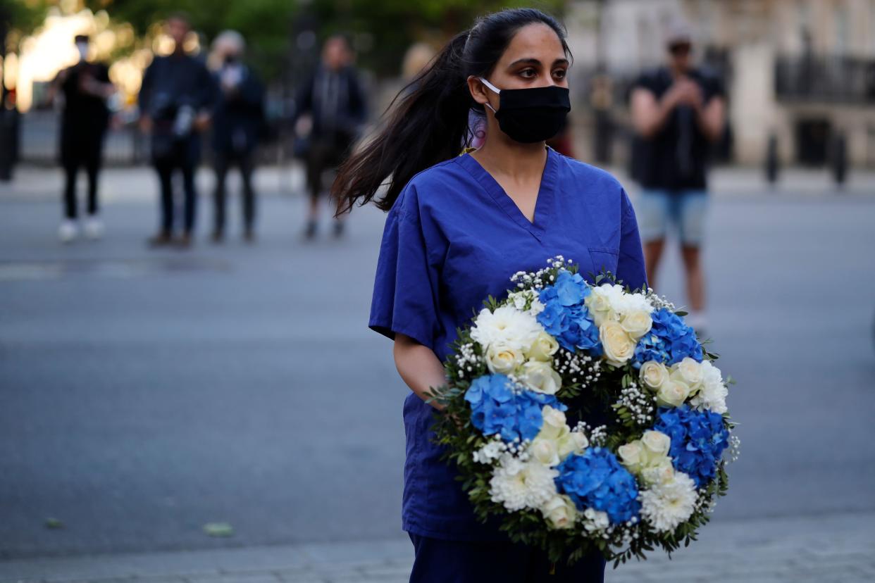 A doctor joins a silent protest during a national "clap for carers" to show thanks for the work of Britain's NHS (National Health Service) workers and other frontline medical staff around the country as they battle with the novel coronavirus pandemic, outside  Downing Street in London on May 28, 2020. (Photo by Tolga Akmen / AFP) (Photo by TOLGA AKMEN/AFP via Getty Images)