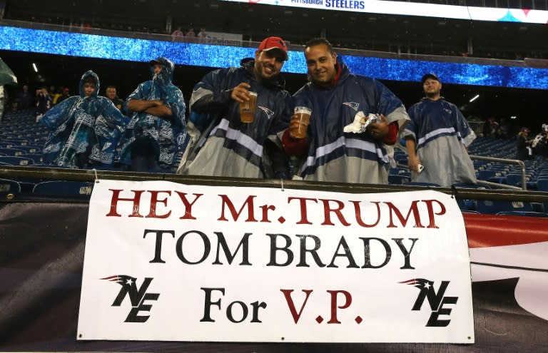 Fans stand with a sign stating "Hey Mr. Trump Tom Brady for V.P."in 2015