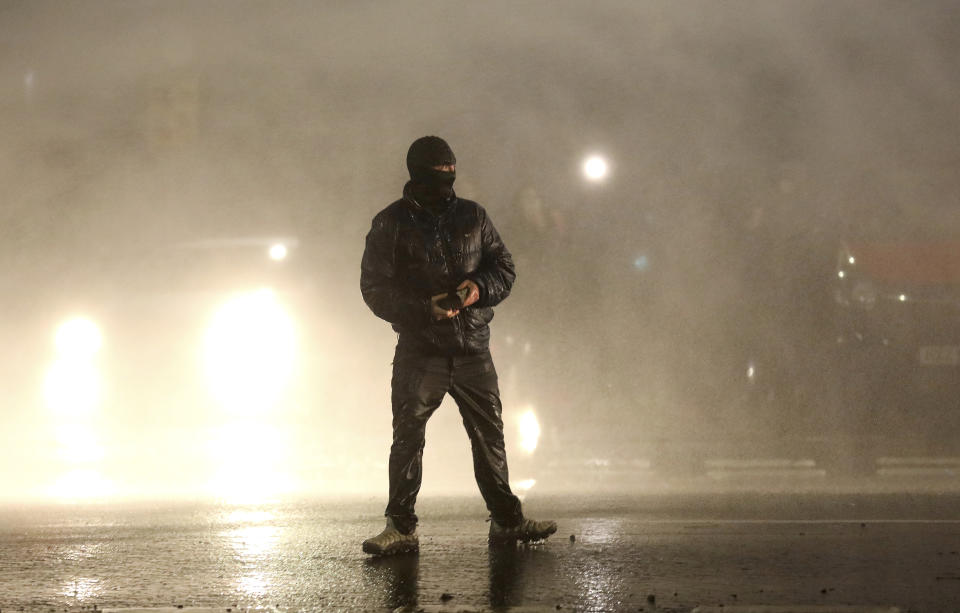 A Nationalist youth confronts police lines near the Peace Wall in West Belfast, Northern Ireland, Thursday, April 8, 2021. Authorities in Northern Ireland sought to restore calm Thursday after Protestant and Catholic youths in Belfast hurled bricks, fireworks and gasoline bombs at police and each other. It was the worst mayhem in a week of street violence in the region, where Britain's exit from the European Union has unsettled an uneasy political balance. (AP Photo/Peter Morrison)