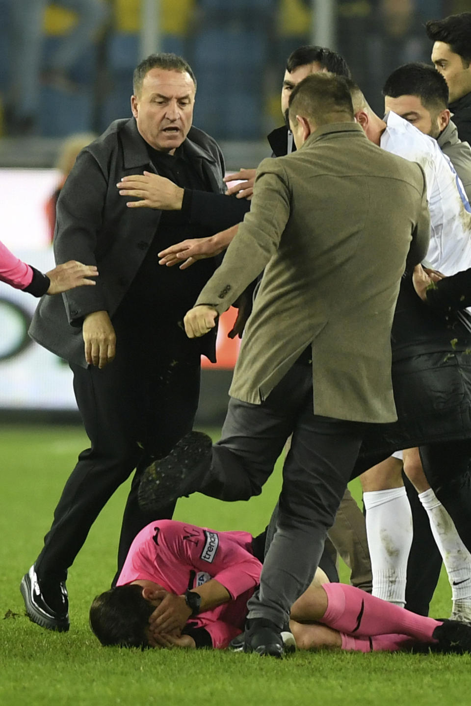 An unidentified man kicks referee Halil Umut Meler who is lying on the ground after he was also punched by MKE Ankaragucu president Faruk Koca, left, at the end of the Turkish Super Lig soccer match between MKE Ankaragucu and Caykur Rizespor in Ankara, Monday, Dec. 11, 2023. The Turkish Football Federation has suspended all league games in the country after a club president punched the referee in the face at the end of a top-flight match. Koca was arrested Tuesday, Dec. 12, 2023, along with two other people on charges of injuring a public official following questioning by prosecutors. (Abdurrahman Antakyali/Depo Photos via AP)