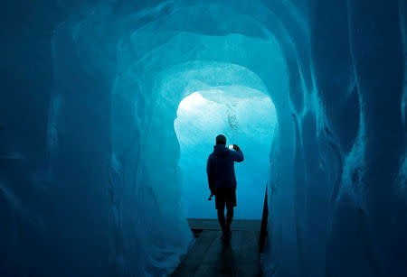 A tourist takes a picture in the Ice Cave at the Rhone Glacier in Furka, Switzerland, September 13, 2018. REUTERS/Denis Balibouse