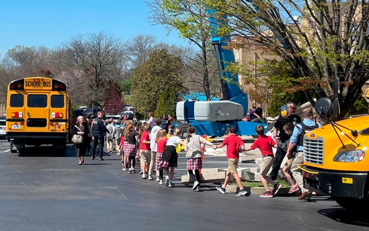 Children hold hands as they are led away from the school - Jonathan Mattise