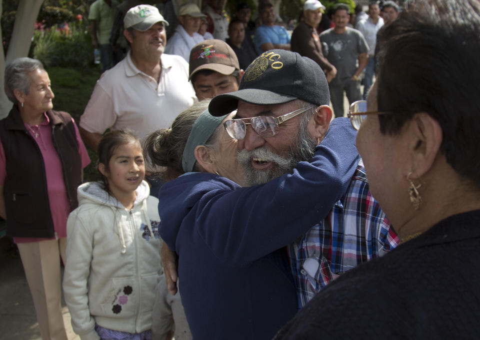 A woman embraces self-defense group spokesman Estanislao Beltran in Tancitaro, Michoacan, Mexico, Thursday, Jan. 16, 2014. Mexico's spreading vigilante movement announced its first big land hand-out, returning 25 avocado orchards to farmers whose properties had been seized by the cartel, which started in drug trafficking and expanded to extortion and economic control. Such moves are expanding the strength and popularity of the vigilantes even as the government demands they disarm. (AP Photo/Eduardo Verdugo)