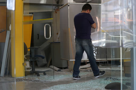 An employee walks next to broken glass at a damaged branch of Banco do Brasil after a gang caused an explosion in a part of the bank in an attempted robbery, in Guararema, near Sao Paulo, Brazil April 4, 2019. REUTERS/Amanda Perobelli