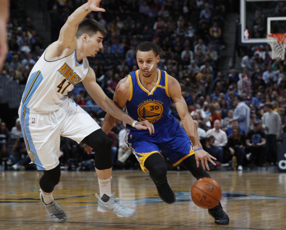 Golden State Warriors guard Stephen Curry, right, drives past Denver Nuggets forward Juancho Hernangomez, of Spain, to the rim in the first half of an NBA basketball game, Monday, Feb. 13, 201, in Denver. (AP Photo/David Zalubowski)