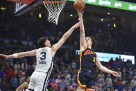 Oklahoma City Thunder guard Josh Giddey, right, shoots over Memphis Grizzlies forward Jake LaRavia, left, in the first half of an NBA basketball game, Sunday, March. 10, 2024, in Oklahoma City. (AP Photo/Kyle Phillips)